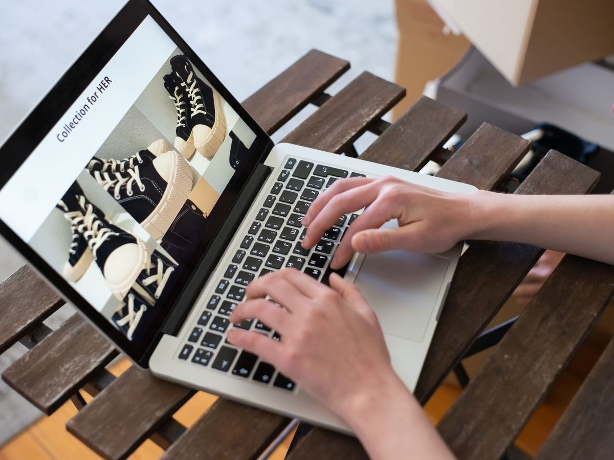 Illustrative photo: a person working on a laptop that shows an online store's product catalogue, with a shipping box nearby